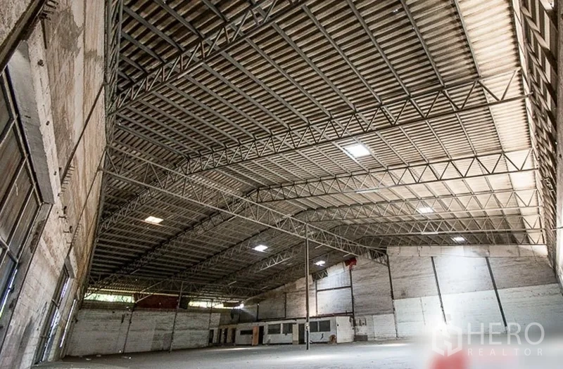 Warehouse for rent in Bang Phli, Samut Prakan - Spacious warehouse interior featuring a high clear-span steel truss roof with skylight panels.