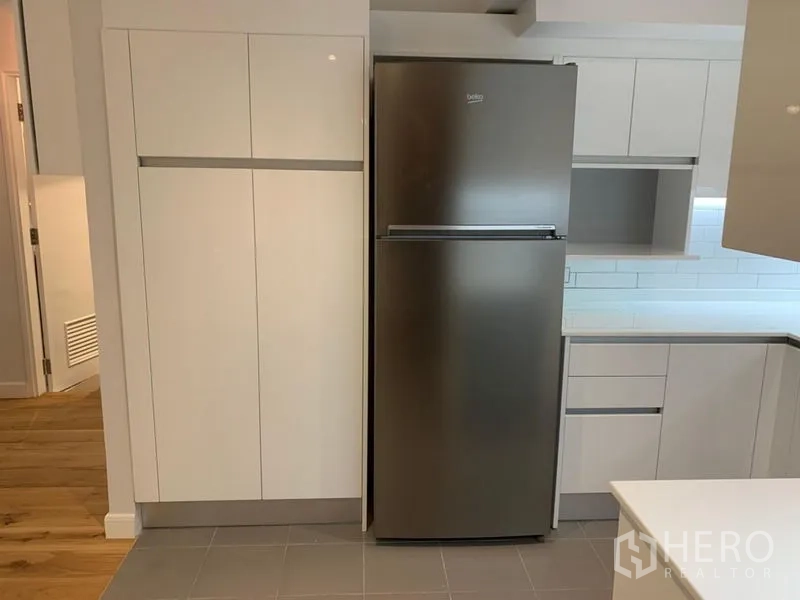 Condominium for sale in Watthana, Bangkok - Tall stainless refrigerator beside sleek white cabinetry.