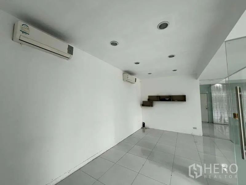 Showroom for rent - Air-conditioned office room with white tiles and wall shelves.