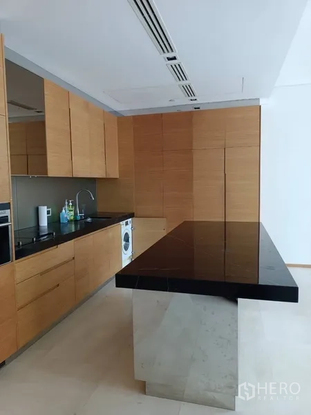 Condominium for rent or sale in Bang Rak, Bangkok - Modern kitchen with black stone island, wood cabinetry and built-in appliances.