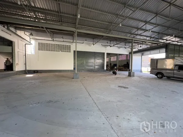 Warehouse for rent in Bang Na, Bangkok - Large covered loading yard with high roof and parked vehicles.