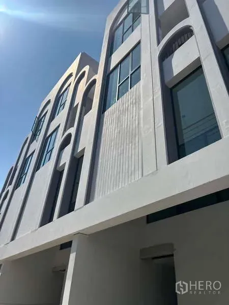 Townhouse for sale - Angled view of minimalist townhouse façade with vertical slat detailing and large glass windows above the carport.