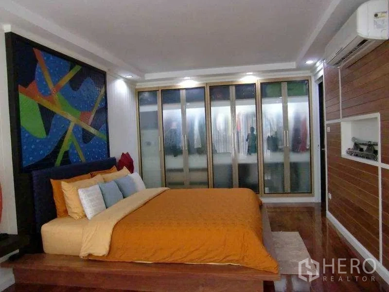 公寓 出租或出售在Watthana, Bangkok - 主卧带平台床与彩色墙面艺术，整面磨砂玻璃衣柜，瓦他那区。