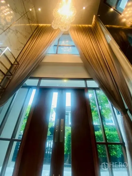独立式住宅 出租在Prawet, Bangkok - 挑高门厅，水晶吊灯、落地窗与长帘相映。