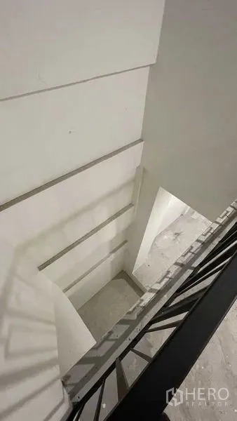 Townhouse for sale in Prawet, Bangkok - Upper-floor landing and staircase with white walls and a black rail.
