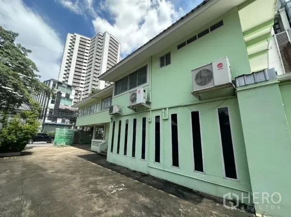 Retail Space for rent in Watthana, Bangkok - Exterior side with vertical windows and multiple A/C units, city towers behind.