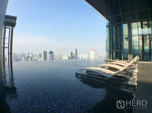 Condominium for rent in Khlong Toei, Bangkok - Rooftop infinity swimming pool with sun loungers overlooking the Bangkok city skyline.