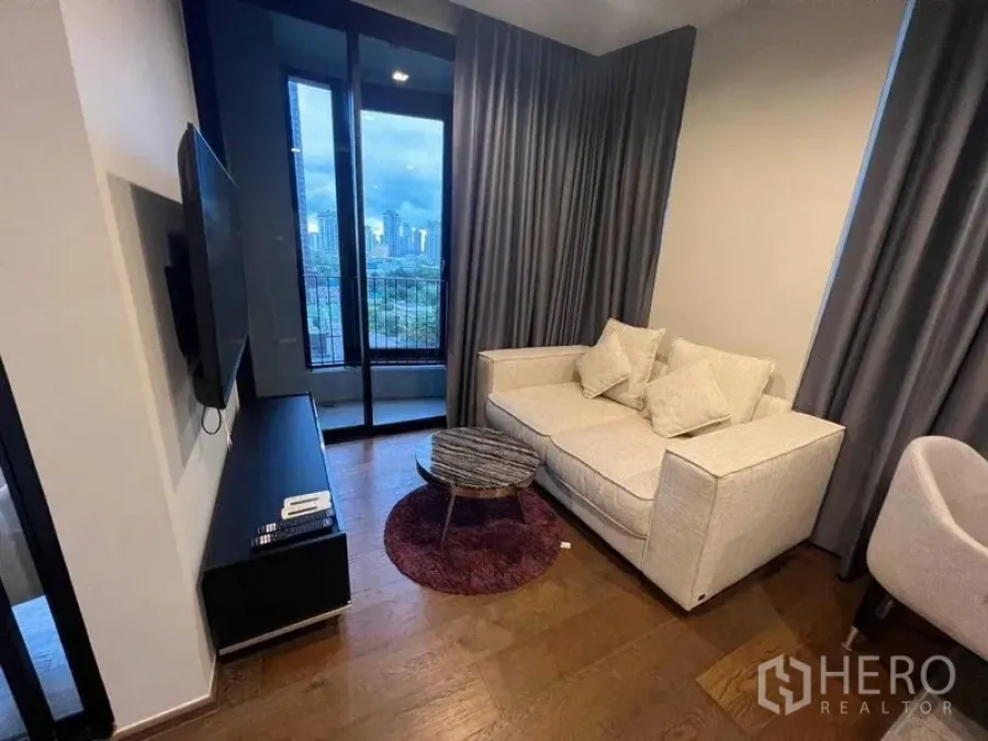 公寓 出租在Khlong Toei, Bangkok - 客厅另一视角，沙发、电视柜与阳台城市景观。