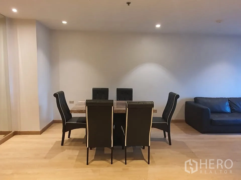 Condominium for rent in Watthana, Bangkok - Dining area with six-seat table and upholstered chairs adjacent to the living room.