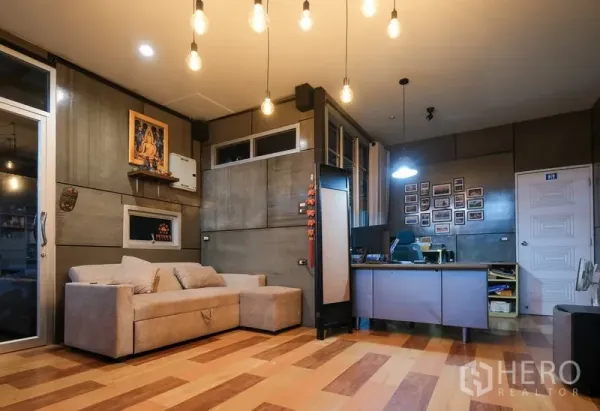 Warehouse for rent in Bueng Kum, Bangkok - Cozy office lounge with sofa, work desk, and concrete-style walls under warm pendant lighting.