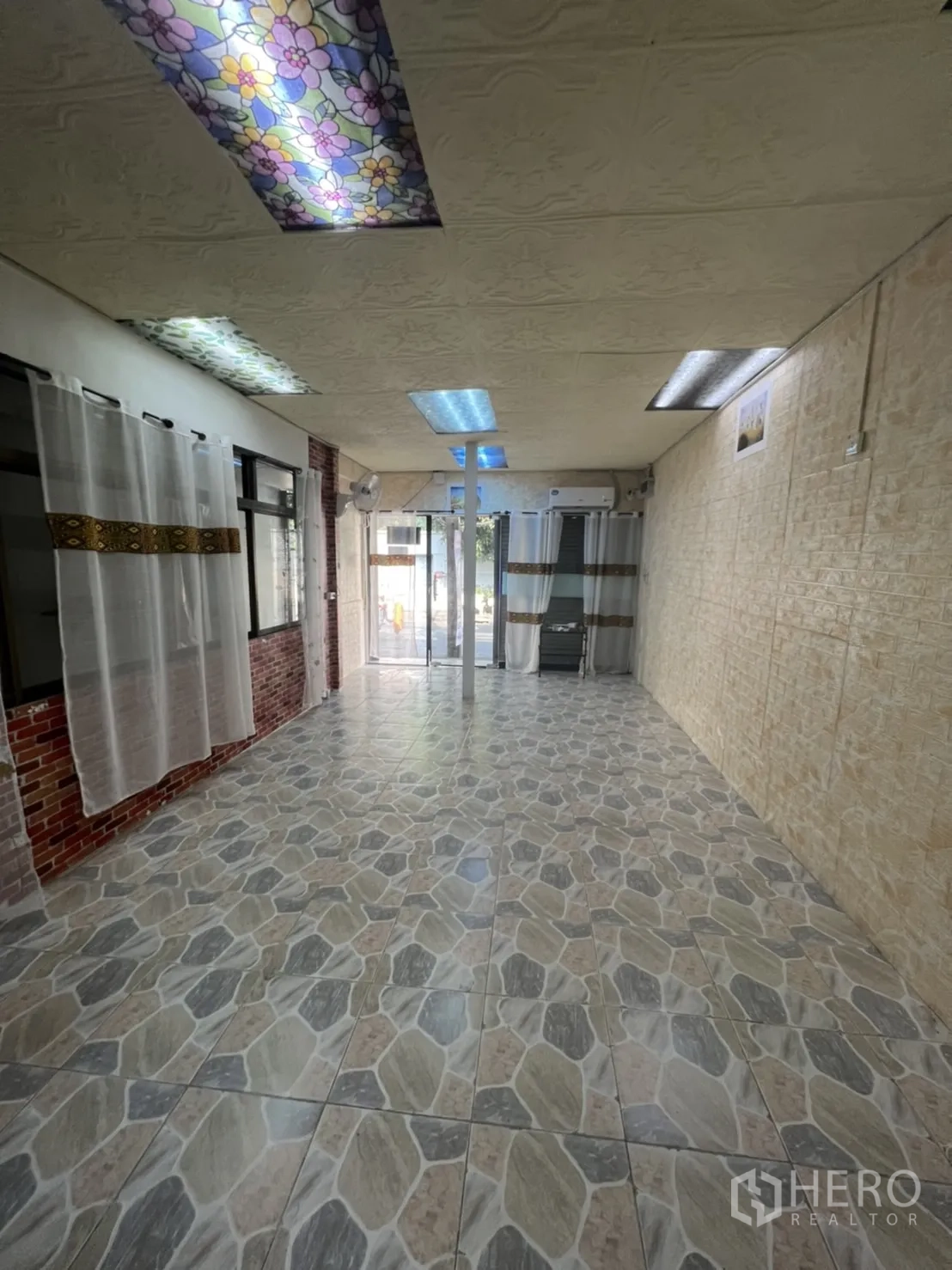Retail Space for rent in Watthana, Bangkok - Open-plan retail interior with stone-pattern floor tiles, glass entrance, brick accent and fluorescent lighting.