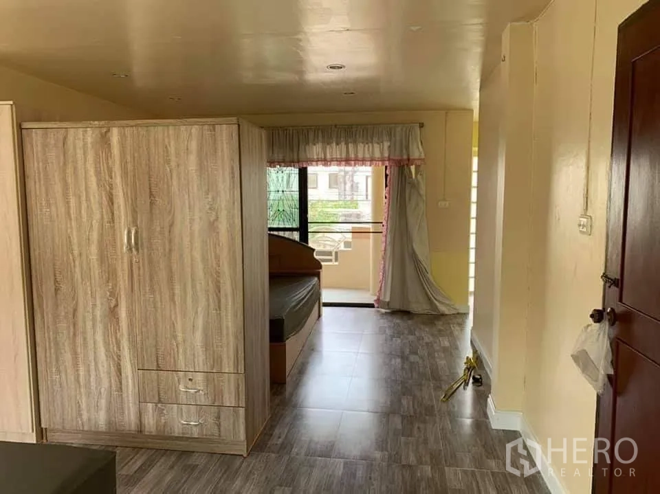 Townhouse for rent in Phra Khanong, Bangkok - Bedroom corridor with wardrobe leading to a small balcony and abundant natural light.