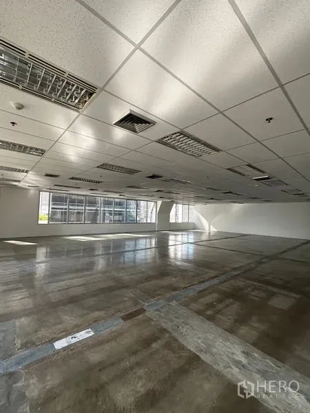 Office Space for rent in Pathum Wan, Bangkok - Expansive vacant office floor with drop ceiling lighting, polished flooring, and windows on two sides.