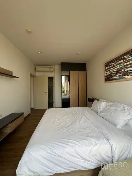 Condominium for rent in Watthana, Bangkok - Master bedroom view toward wardrobe and doorway with wood flooring and air conditioner.