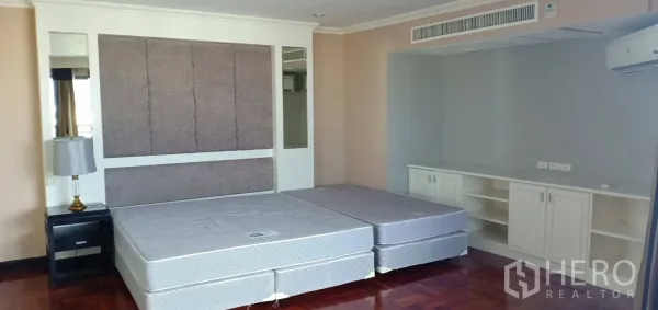 Condominium for rent in Watthana, Bangkok - Spacious master bedroom with twin mattresses, padded headboard, built-in cabinetry and air conditioning.