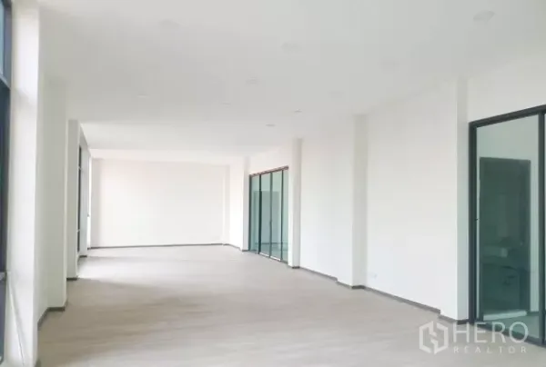Warehouse for rent in Mueang Samut Sakhon, Samut Sakhon - Open-plan upstairs office area with white walls, wood-look flooring and multiple sliding glass doors.