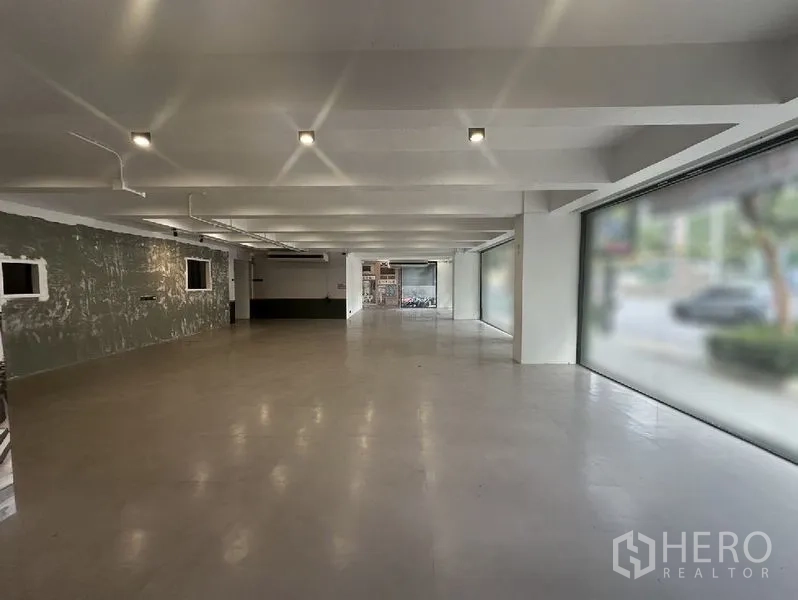 Retail Space for rent in Bang Rak, Bangkok - Long, flexible sales floor with multiple display windows on both sides and a textured feature wall.