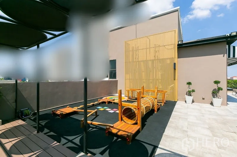 Apartment for rent in Watthana, Bangkok - Rooftop children’s playground with wooden climbing equipment under a canopy.