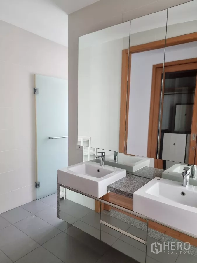 Condominium for rent in Khlong Toei, Bangkok - Double-vanity bathroom with wide mirror and storage.