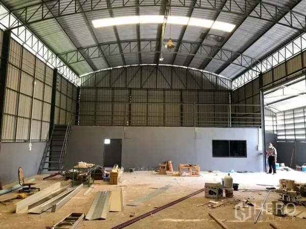 货栈 出租在Lam Luk Ka, Pathum Thani - 仓库内部高屋顶，夹层平台、楼梯、混凝土地面与大滑门。