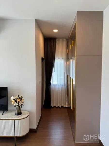 Detached House for rent or sale in Bang Phli, Samut Prakan - Bedroom corridor with built-in wardrobe featuring gold pulls and a side cabinet.