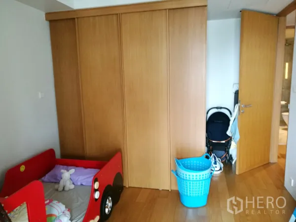 Condominium for rent or sale in Sathon, Bangkok - Secondary bedroom with built-in wooden wardrobe and warm wood flooring.