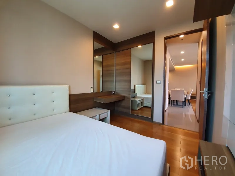 Condominium for rent in Bang Rak, Bangkok - Second bedroom with built-in wardrobe, mirrored panels, and a dressing table.