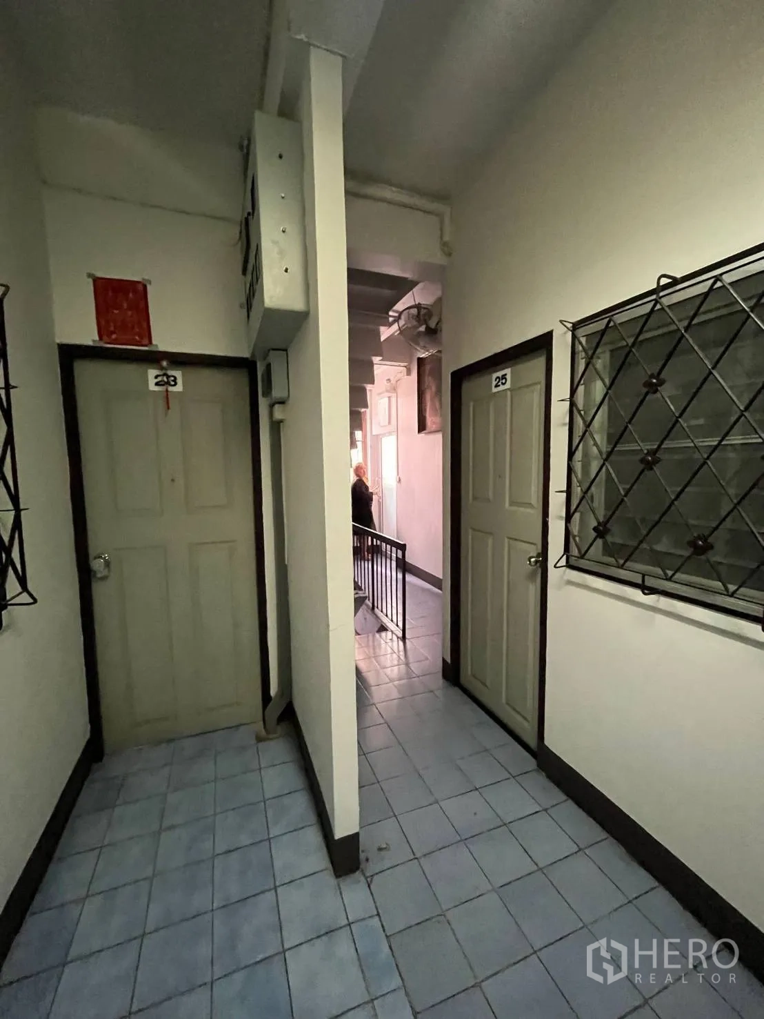Shophouse for rent in Khlong Toei, Bangkok - Narrow passage with room doors and barred windows beside a staircase.