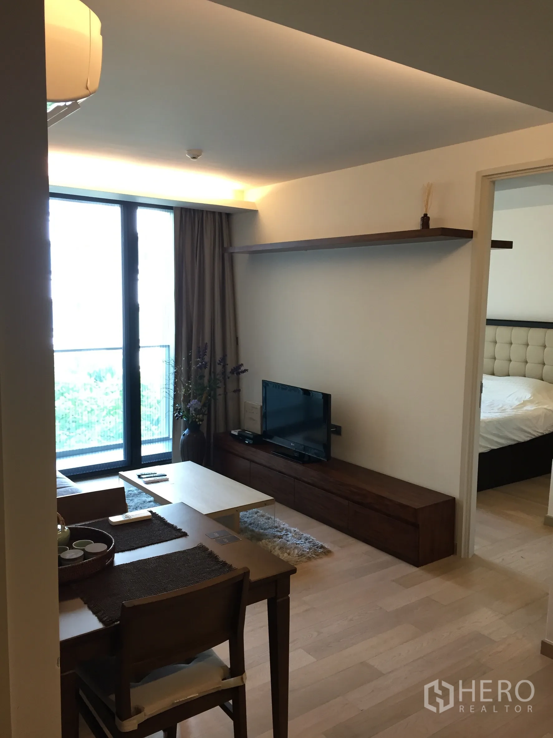 Condominium for rent or sale in Watthana, Bangkok - Bright living room with TV console, coffee table, sliding glass doors to the balcony, and a floating wall shelf.