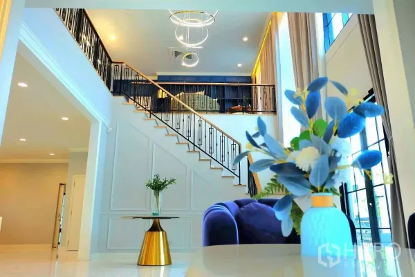 บ้าน ให้เช่าในBang Phli, Samut Prakan - โถงรับแขกเพดานสูง โดดเด่นด้วยบันไดเหล็กและโคมไฟระย้าดีไซน์วงแหวน.