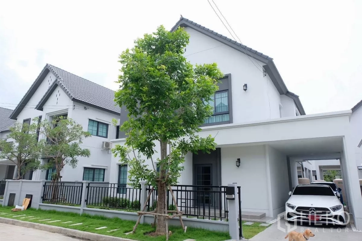 独立式住宅 出售在Bang Phli, Samut Prakan - 现代两层独栋别墅外观，白色立面，带车棚、草坪与金属围栏