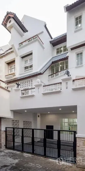 Townhouse for sale - Renovated multi-storey townhouse exterior with white facade, balconies and a secure black gate.