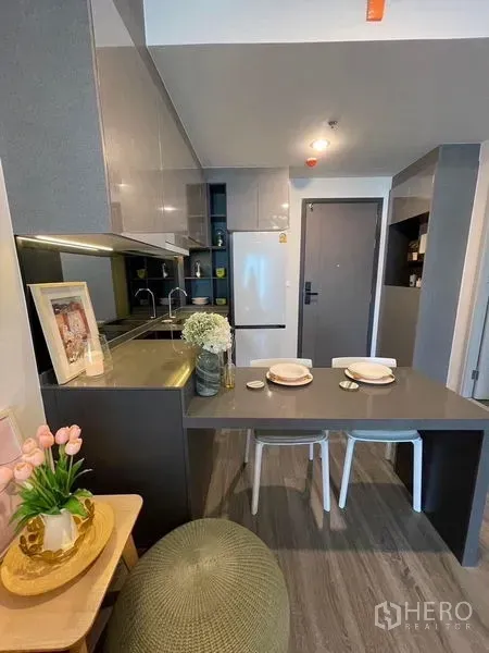 Condominium for rent - Compact modern kitchen with glossy cabinets, refrigerator, sink and a two-seat dining counter.
