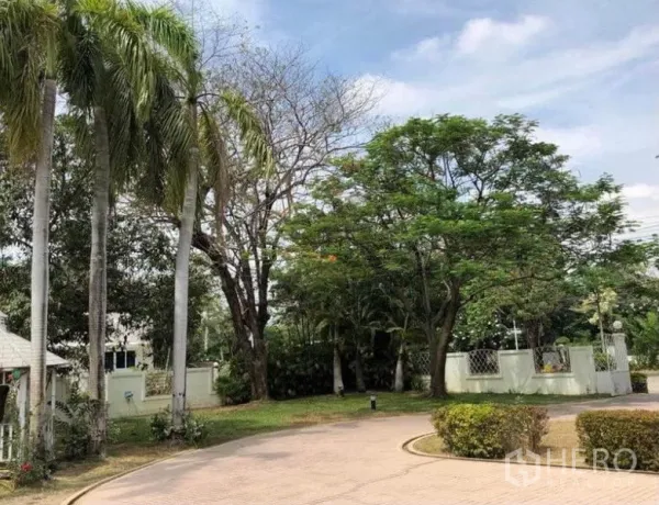 บ้าน ขายในMueang Samut Prakan, Samut Prakan - ถนนโค้งหน้าบ้านรายล้อมด้วยปาล์มและไม้ใหญ่ใกล้ประตูรั้ว