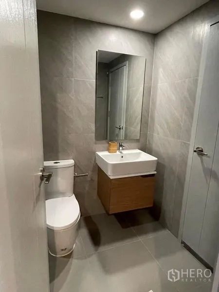 Condominium for rent - Contemporary bathroom with tiled walls, vanity sink, mirror and toilet.