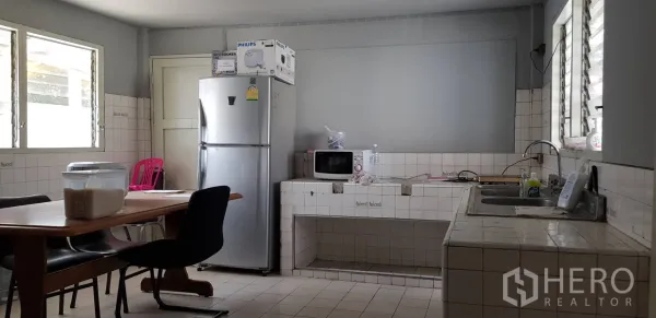 联排别墅 出租在Khlong Toei, Bangkok - 瓷砖厨房，配冰箱、微波炉、双水槽与用餐桌。