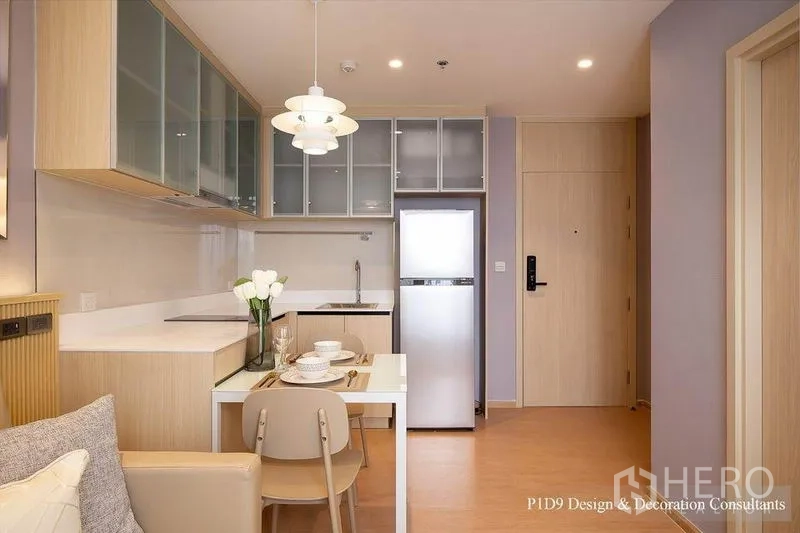 公寓 出租在Watthana, Bangkok - 厨房与入户视角，餐桌上方吊灯，灶台、水槽和高冰箱。