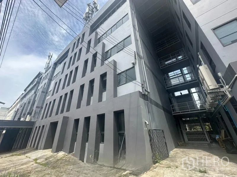 Warehouse for rent in Bang Phli, Samut Prakan - Angled exterior showing the modern grey facade and side container access lane.