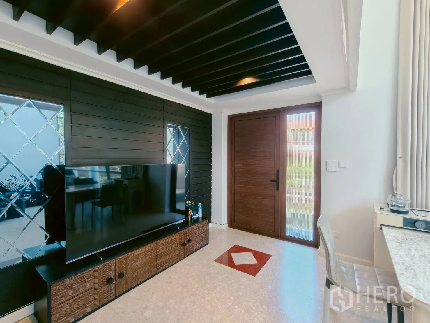 Detached House for rent in Lat Krabang, Bangkok - Living area with large TV console, black slat ceiling and wooden front door.
