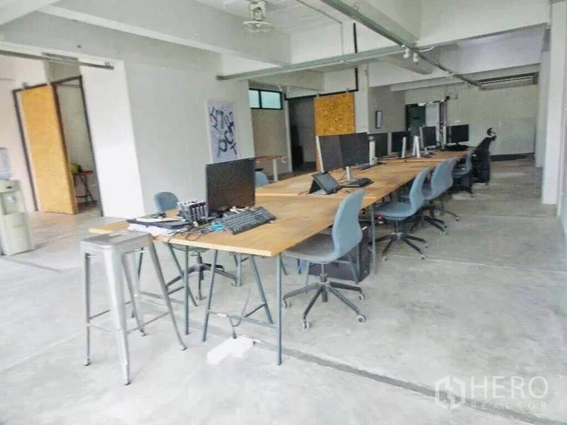 Home Office for rent or sale in Din Daeng, Bangkok - Long shared workstation area with wooden tables, task chairs and exposed ceiling.