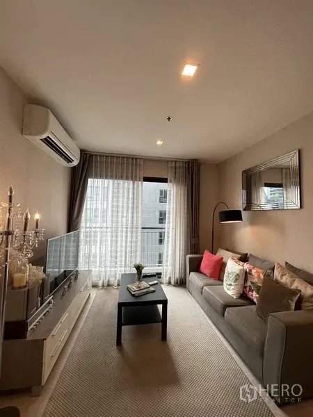 公寓 出租或出售在Khlong Toei, Bangkok - 明亮客厅，灰色沙发、电视柜与落地窗薄纱窗帘。