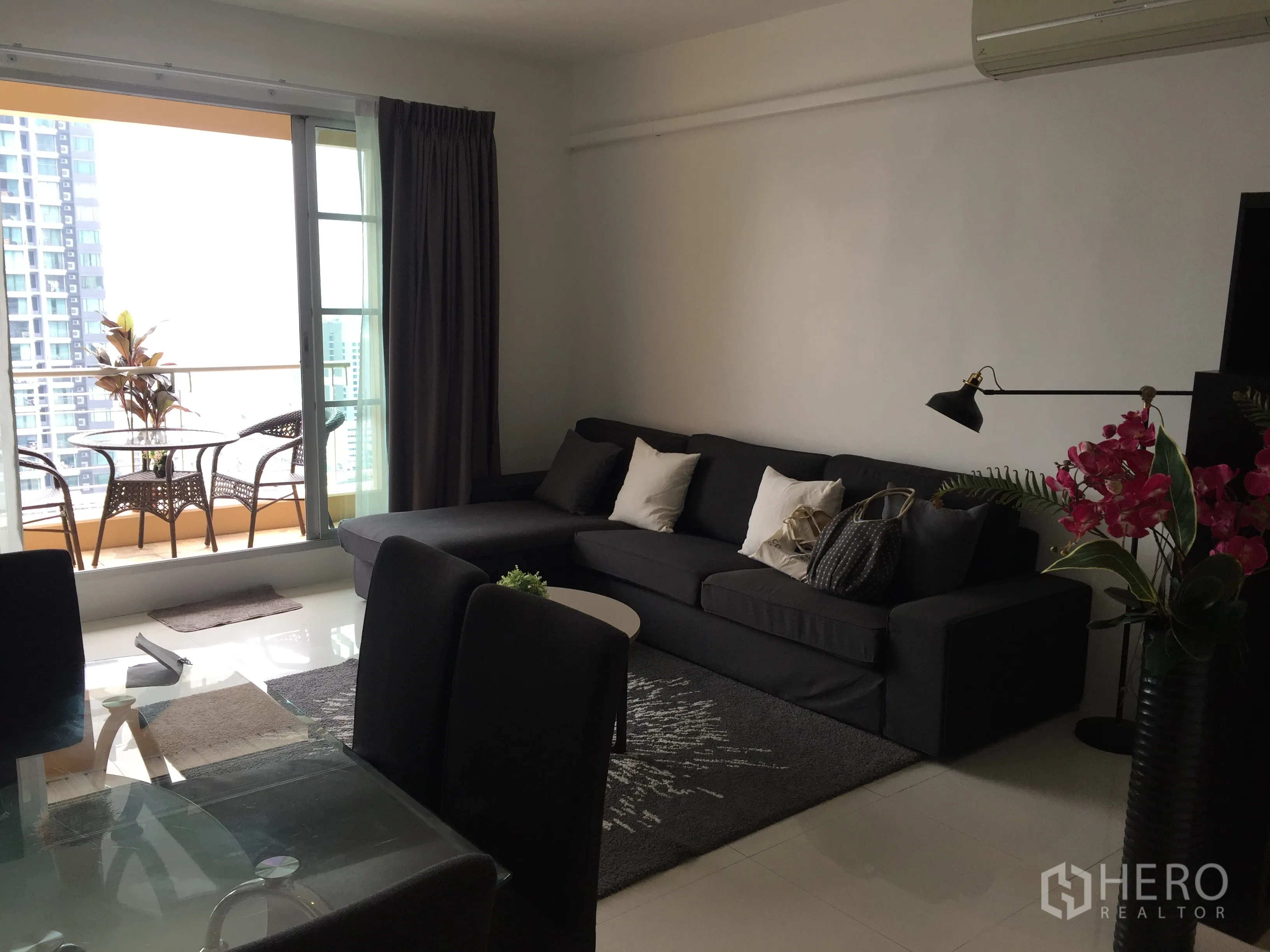公寓 出租在Ratchathewi, Bangkok - 开放式客厅，深色转角沙发与餐桌，连通观景阳台。