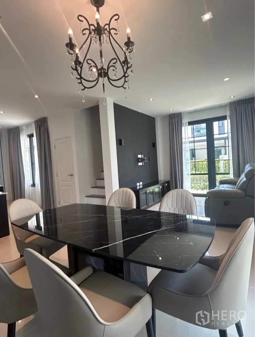 Semi-detached House for rent in Bang Phli, Samut Prakan - Open-plan dining and living area with chandelier, staircase and accent wall.