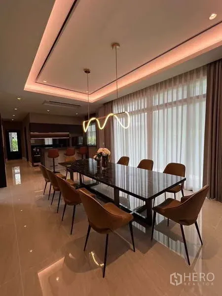 Detached House for rent or sale in Lat Krabang, Bangkok - Elegant dining room with a long table, pendant lights, and floor-to-ceiling curtains.