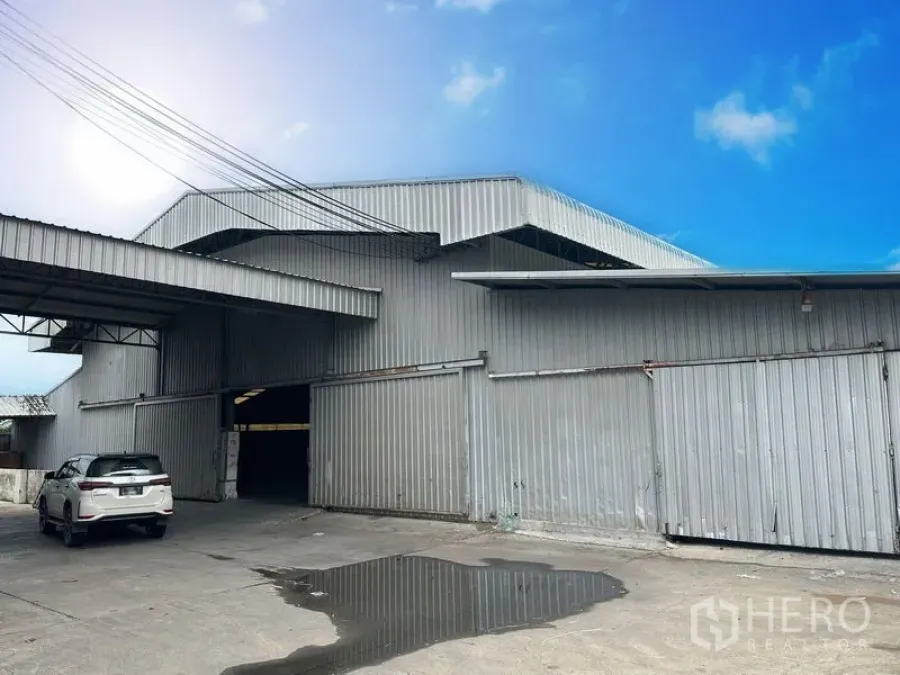 Factory for rent in Lat Lum Kaeo, Pathum Thani - Front facade of industrial building with large sliding metal doors, covered loading bay and parking area.