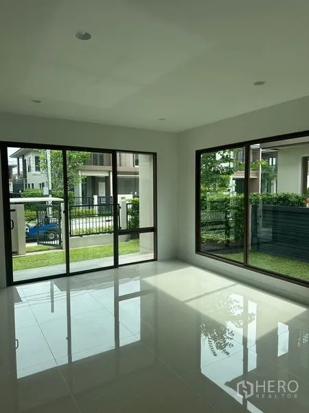 独立式住宅 出租在Bang Kapi, Bangkok - 客厅明亮，抛光地砖，转角推拉落地窗连接花园。