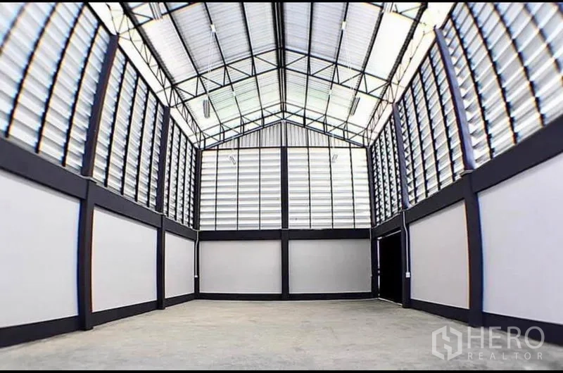 Factory for rent in Lat Lum Kaeo, Pathum Thani - High-ceiling warehouse interior with steel truss roof, louvered ventilation panels and a concrete floor.