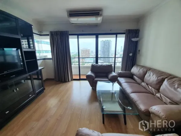 Condominium for rent in Sathon, Bangkok - Living area with balcony access and skyline view of Sathon from floor-to-ceiling sliding glass doors.