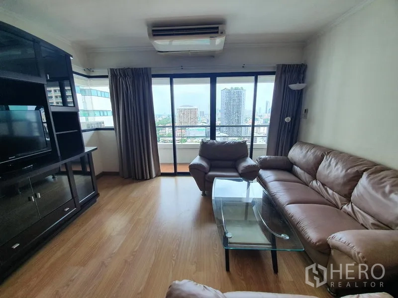 Condominium for rent in Sathon, Bangkok - Living area with balcony access and skyline view of Sathon from floor-to-ceiling sliding glass doors.