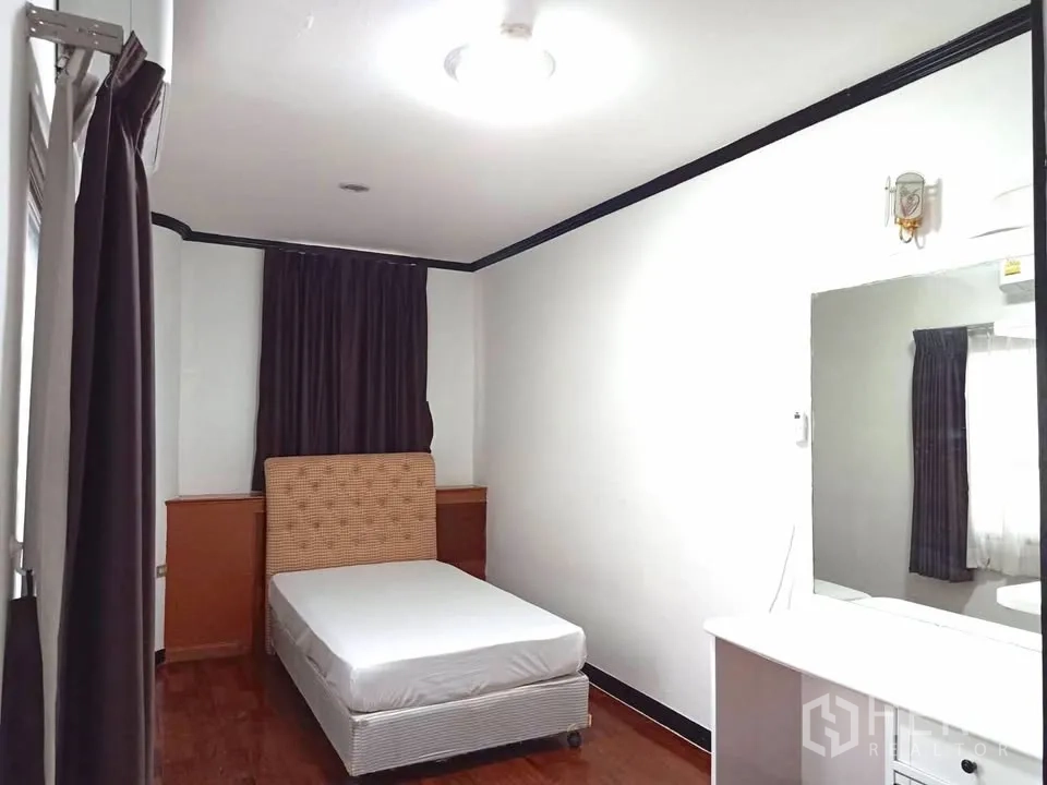 Condominium for rent in Watthana, Bangkok - Cozy bedroom with single bed, vanity, and dark curtains.